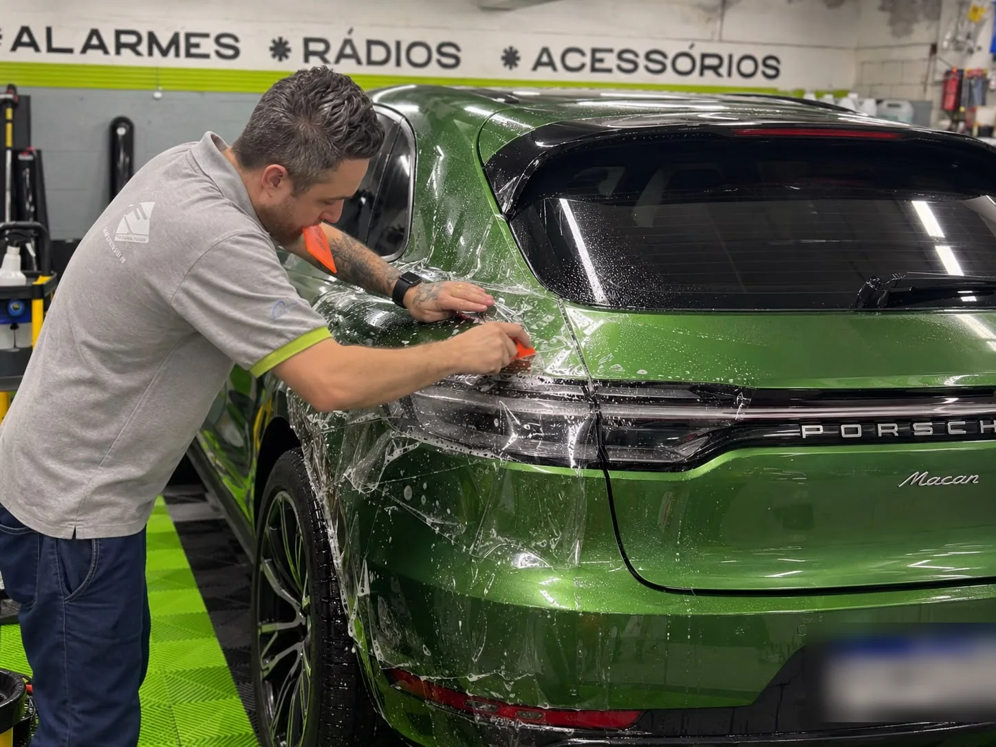 Aplicação real de película PPF em um Porsche verde na Thunder Som, com placa do veículo protegida